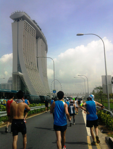Imposing view of Marina Bay Sands; runners trudging under the scorching heat of the sun